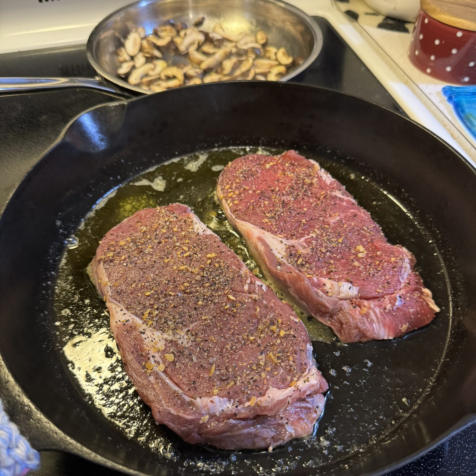 ribeyes in a cast iron with mushrooms